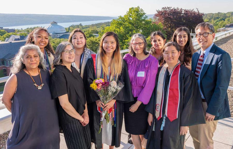 a group of people in graduation gowns and formal wear smiling on a balcony