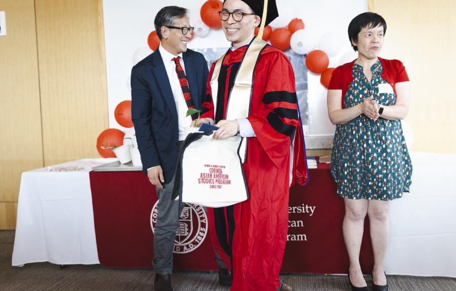a graduating student in a red robe smiles at the camera