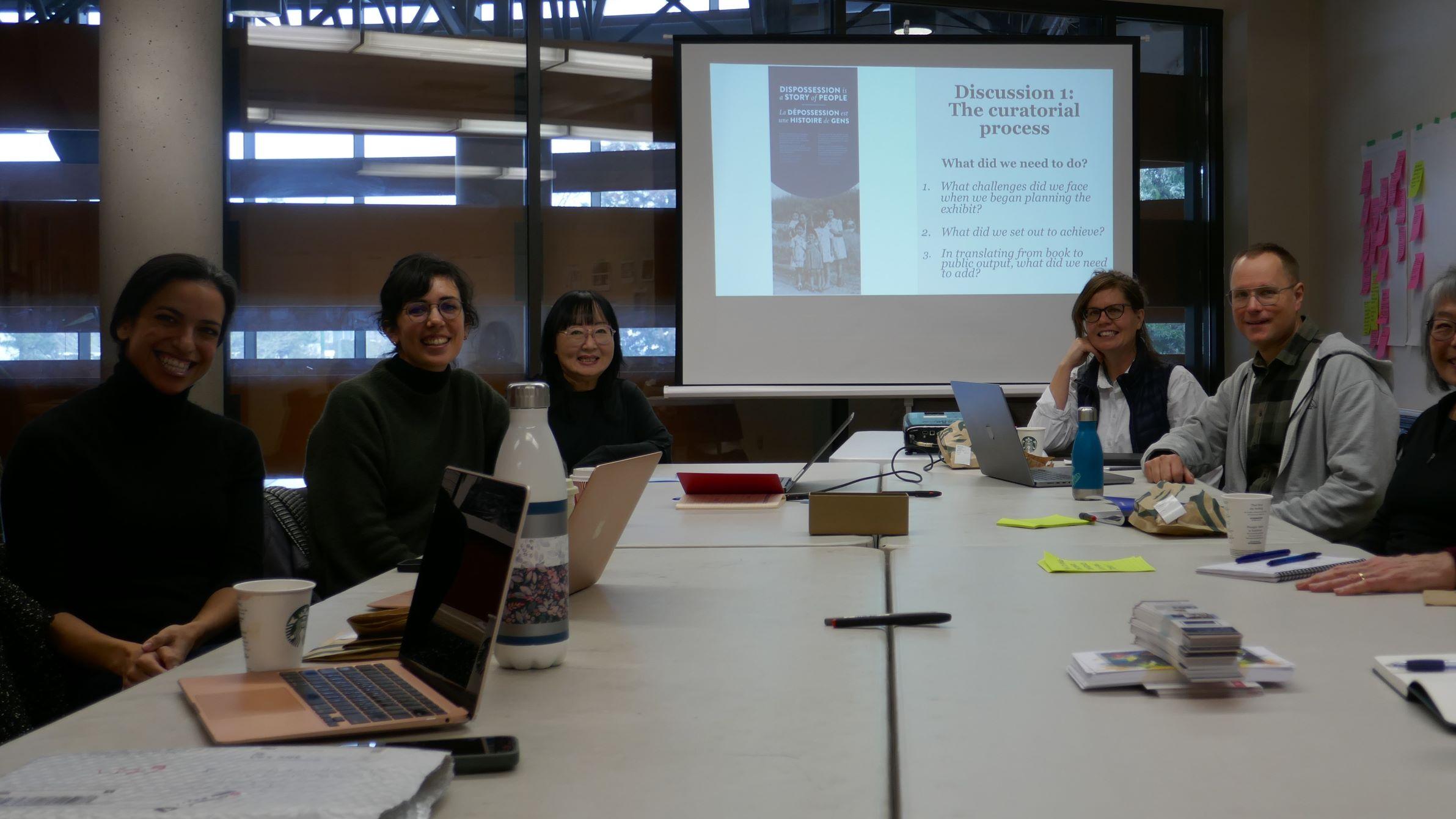 six people smiling at the camera and sitting around a table
