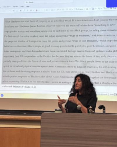 a person speaking in front of a screen with a quote